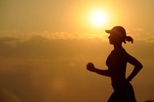 woman jogging at dusk or dawn with clouds in the background