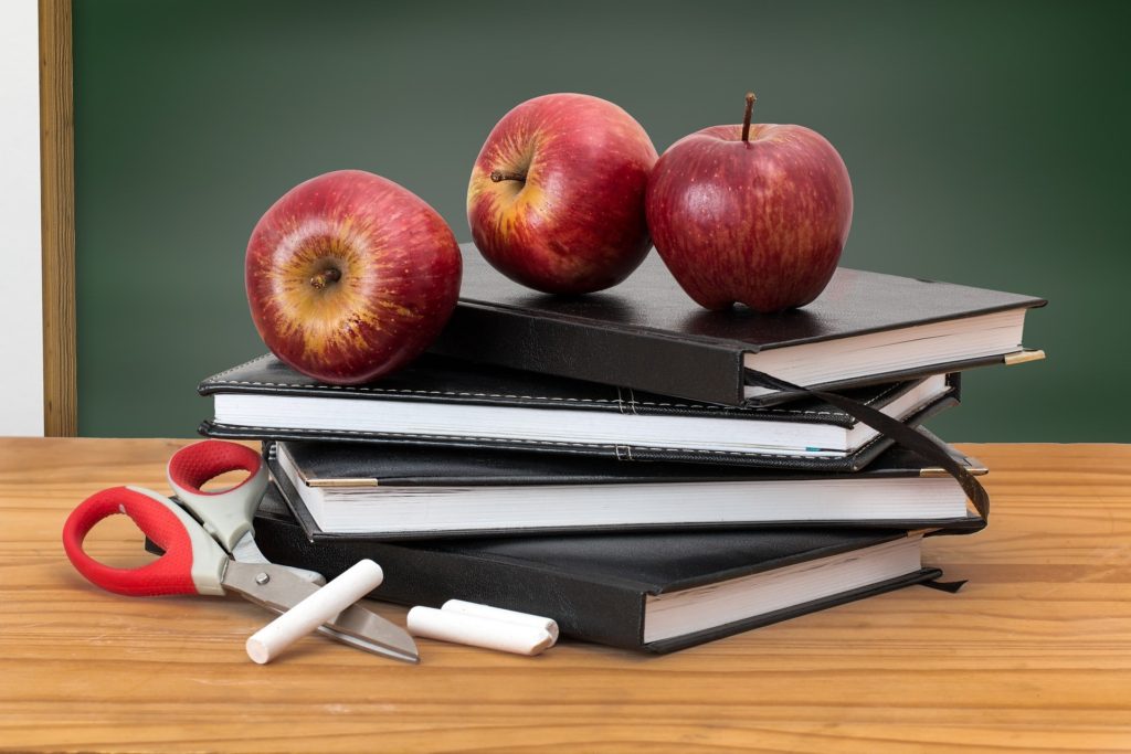 back to school three apples on top of books chalk scissors desk black board chalk board nutrition information health class